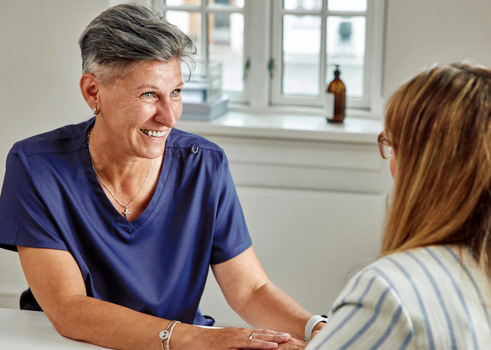 Healthcare professional smiling and holding patient's hand